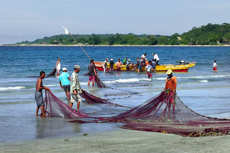 Fishermen working together hauling a net on a Philippine beach
