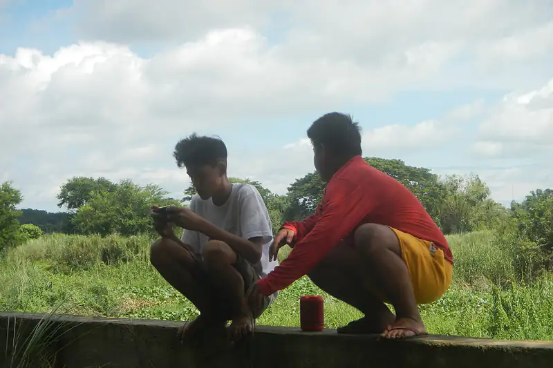 Two young men in Bustos, Bulacan looking at a phone together outdoors